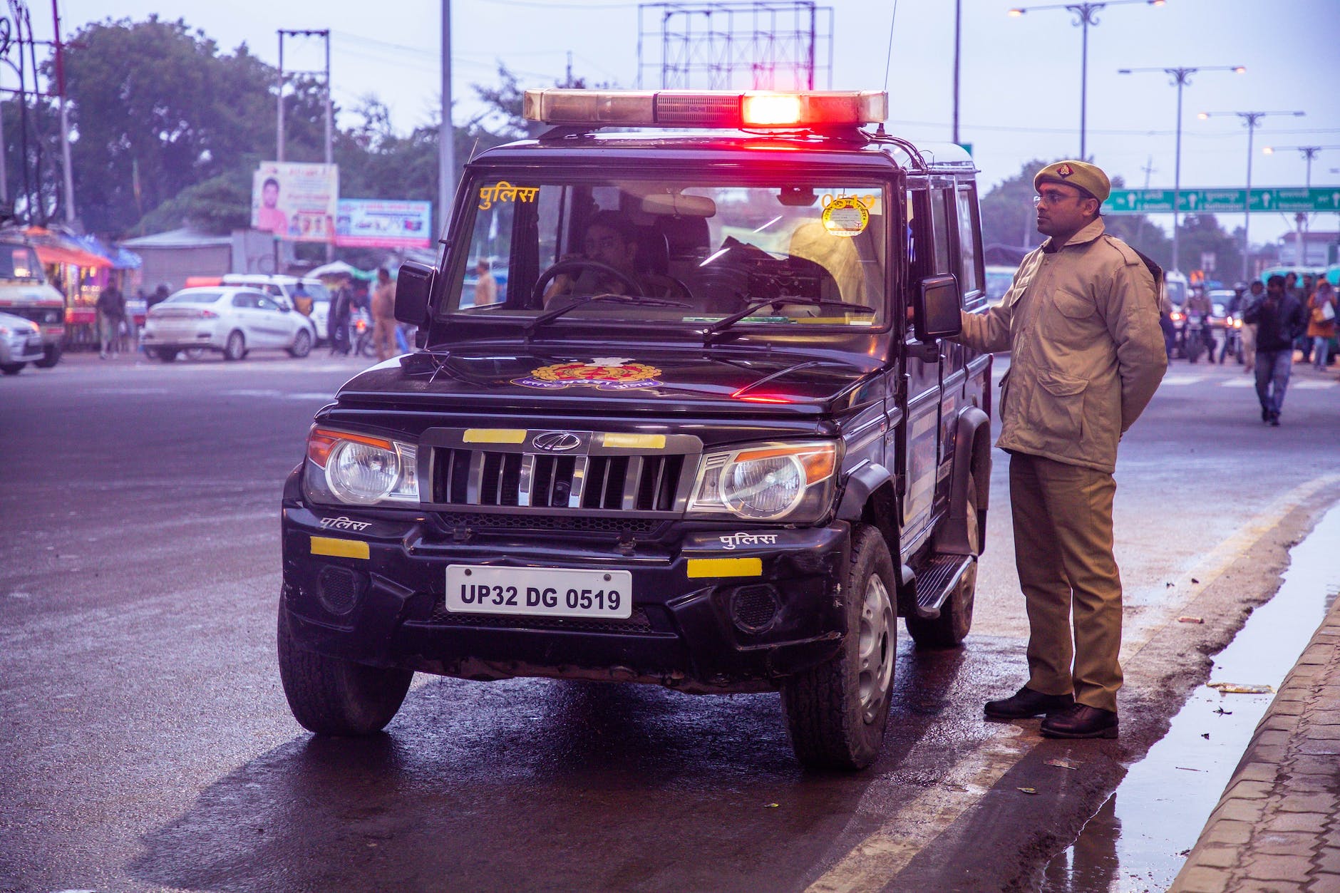 a policeman standing beside a police car by the roadside